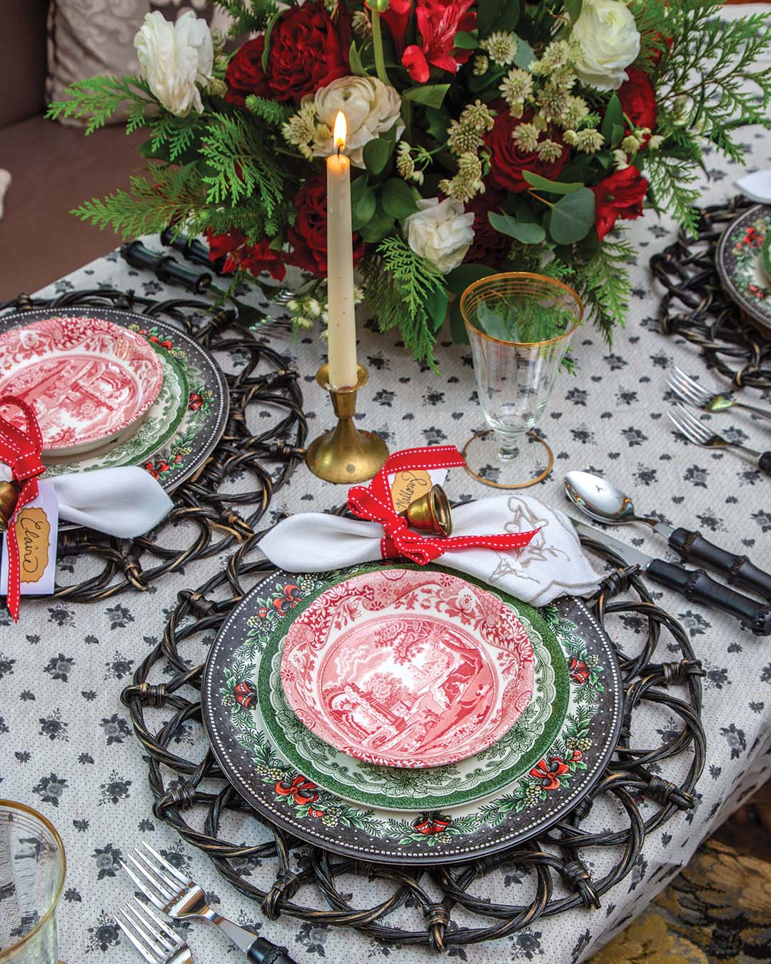 Festive holiday dishware catches the eye, each place setting embellished with a personalized napkin. Bright red ribbons and golden bells add a touch of whimsy.