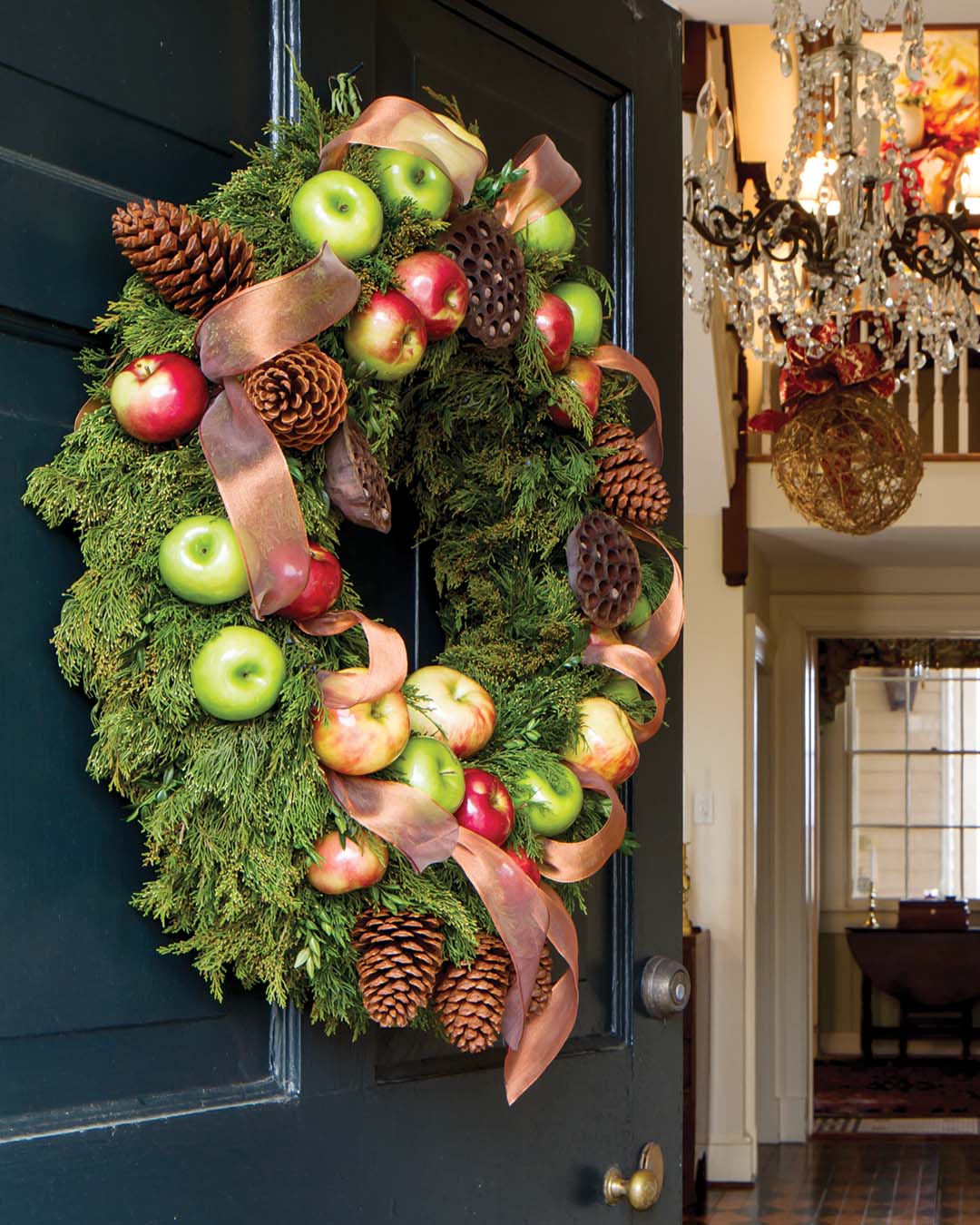 A variety of pine cones and plump apples enlivens a lush ring of evergreens, setting the stage for the heartfelt welcome inside.