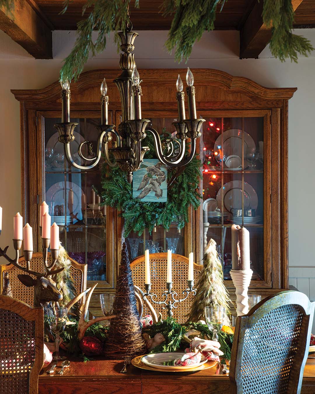 In the dining room, cane-back chairs Stacie inherited from her maternal grandmother surround a table topped with woodland-inspired accents—from the grapevine and feathered trees to the antlers and stag candelabra. A miniature paint-by-numbers canvas featuring a pair of mallard ducks is encircled by a simple wreath.