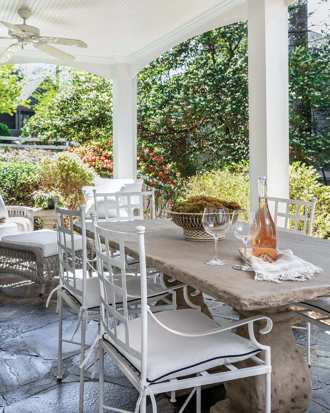 A covered patio is an idyllic setting for outdoor dining, and Virginia outfitted it with a concrete table and white metal chairs. With plenty of shade and inviting wicker chairs, the space offers a spot for the homeowners to enjoy their private oasis.
