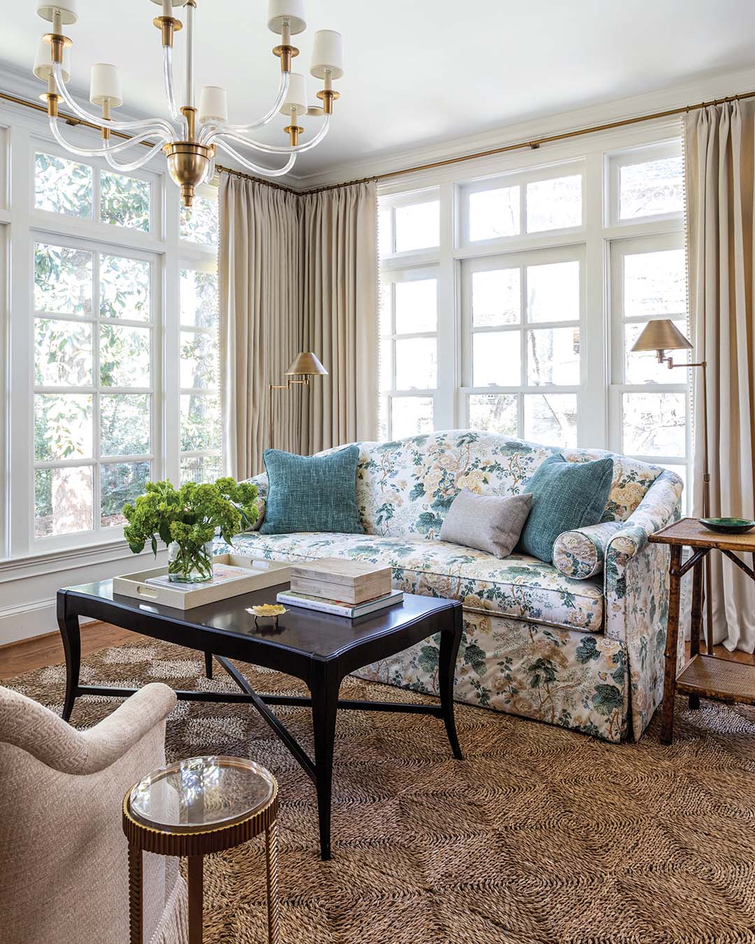 The chintz sofa—bearing a classic Lee Jofa print—is a romantic focal point, which the Visual Comfort chandelier complements with subtle elegance.