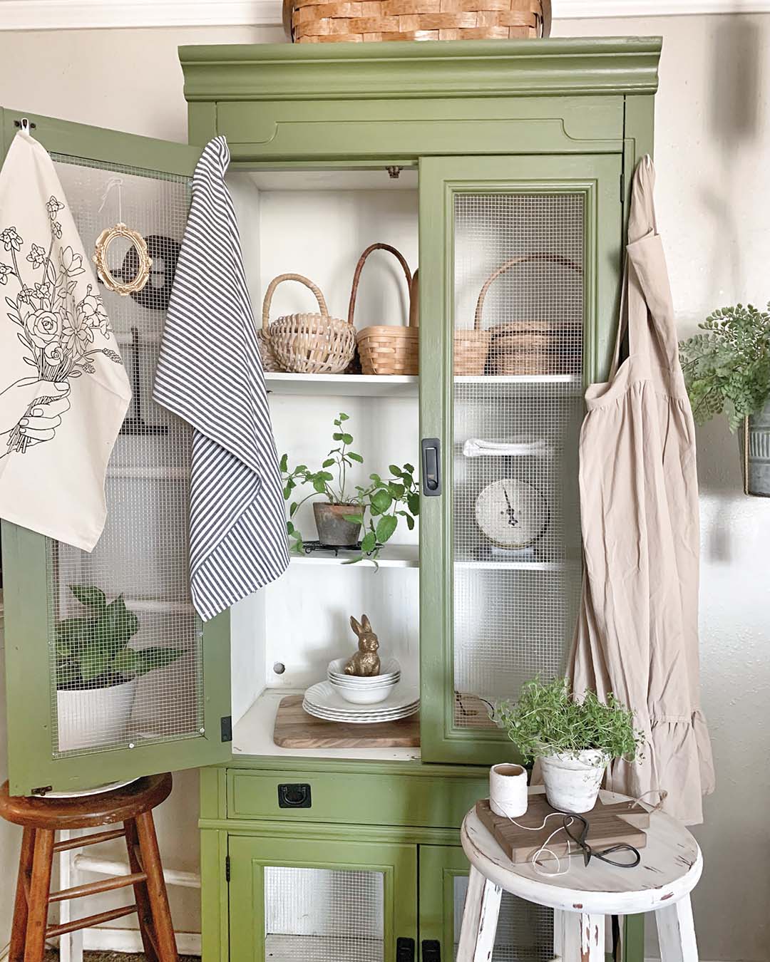 Becca is no stranger to giving fresh, new life to older pieces of furniture. Look no further than her green cabinet, just off the dining room. “My inspiration behind this [piece] was to give it an old antique pie safe feel,” she says. So, the couple painted it, adding wooden shelving in place of the existing glass shelves and wire mesh hardware cloth in place of the glass that was in the doors.