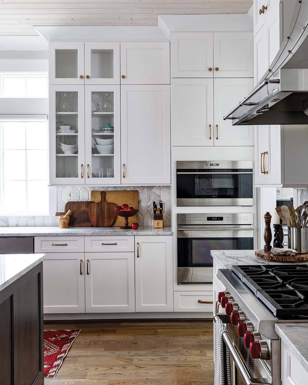 The kitchen is immersed in crisp whites and luxurious Carrara marble countertops and backsplash. An antique runner boasting rich red hues serves as the singular spirited showstopper as it creates common ground between the two locales.