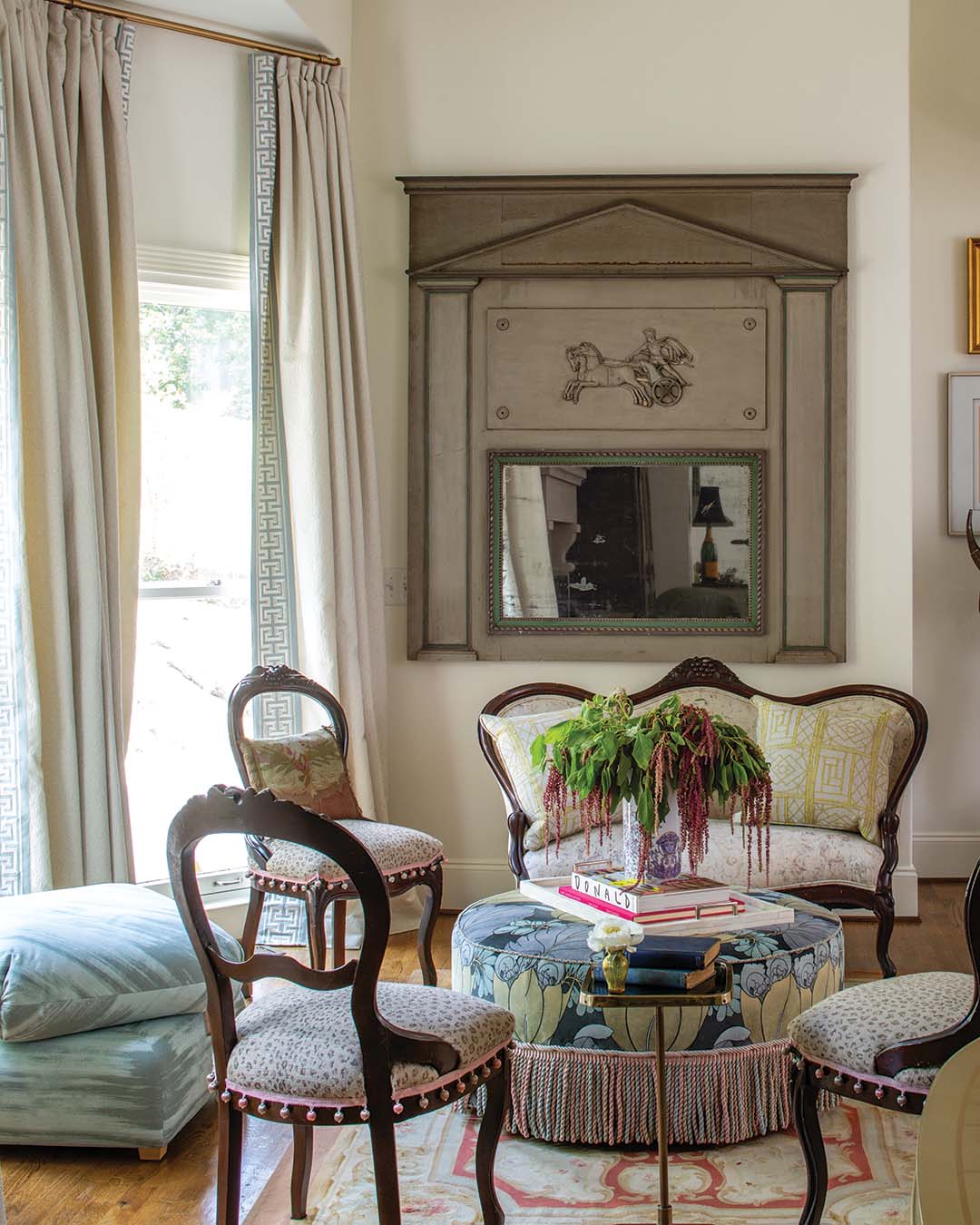 The sitting area centers on the ottoman from the homeowner's childhood room—re-covered and topped with fashion books.